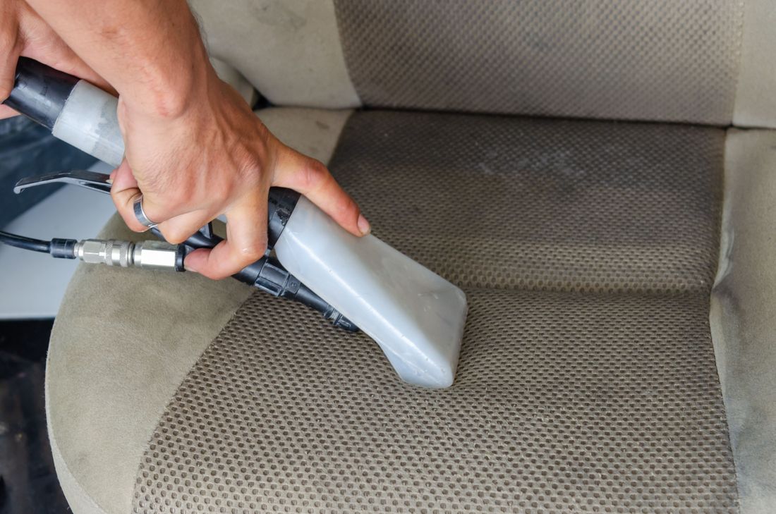 Steam-cleaning a car seat during a deep interior detail